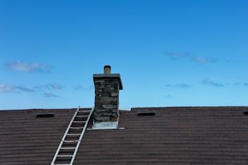 Chimney with a ladder set up for service, similar to homes throughout Eagan, MN